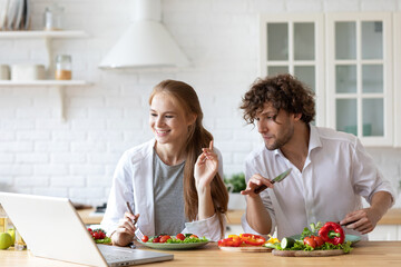 Young couple using the internet to look up recipe. Cooking together salad, having fun in the kitchen.