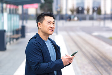 Thinking Asian, business man uses phone, near modern office, and airport