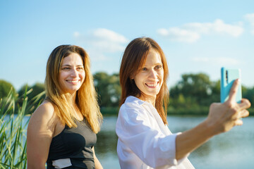 Cheerful happy women friend in nature take selfie by smartphone
