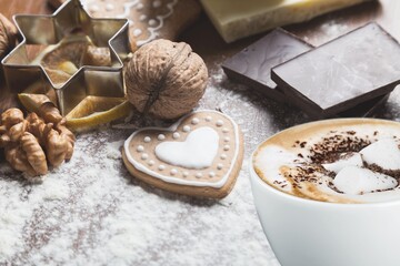 Christmas gingerbread cookies, coffee in stylish white cup, pine cones and fir branches on table.