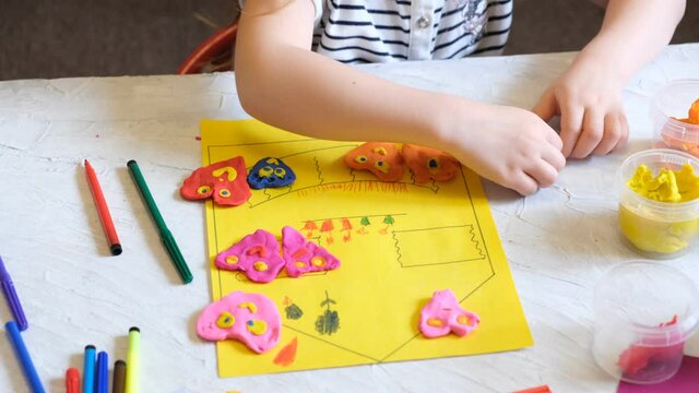 Child playing with modeling clay, plasticine and sculpting heart figurines. Concept of happy family having fun. Kid craft. Home Education game. Early development concept