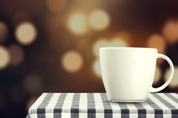 Mug with hot tea standing on a desk with blanket in a cozy room