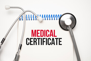 White notepad with the words Medical CERTIFICATE and a stethoscope on a blue backgroundd. Medical...