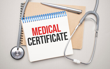 White notepad with the words Medical CERTIFICATE and a stethoscope on a blue backgroundd. Medical concept
