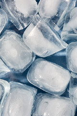 Fototapeta premium Top view of ice cubes in a glass bowl on a blue background