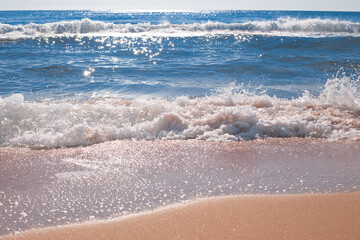 Sea waves with white foam sparkle in the sun on a summer day. Travel and tourism