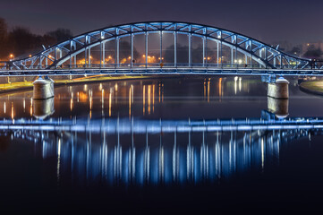 Fototapeta na wymiar Pilsudski steel truss bridge over Vistula river in Krakow in the night