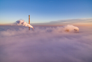 Power plant chimneys and smoke over sea of fog in the morning