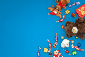 Christmas concept with Plush Toys and candy on pop color blue background with negative copy space.