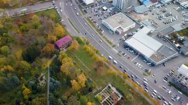 Aerial autumn Kharkiv Botanical Garden near street with lively cars traffic. Tourist attraction in Shevchenko City Garden with modern buildings and scenic sky in Kharkiv, Ukraine