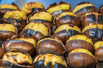 Organic brown chestnuts group roasting over a hot fire.