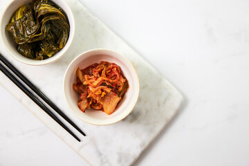 Top view of kimchi and fermented bok choy served in two white bowls - obrazy, fototapety, plakaty