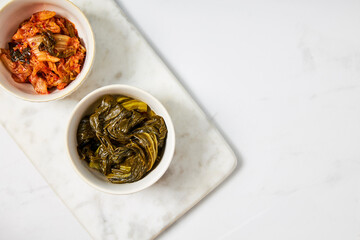 Top view of kimchi and fermented bok choy served in two white bowls