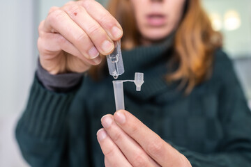 Putting the reactive liquid in the tube. A young woman doing the rapid antigen test at her home, sars-cov-2 tests. Security measures in the coronavirus pandemic