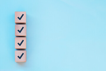 Checklist concept, Check marks on wooden cube blocks, blue background with free copy space