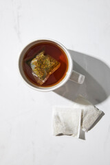 Top view of one white mug with herbal tea and two tea bags
