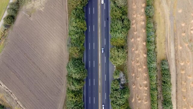 Aerial shot of electrical car driving on country road at summer evening. New SUV vehicle moving fast through highway. Ecology friendly auto riding on electric charge along motorway. Top view