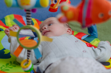 Baby looks at hanging rattles, close-up