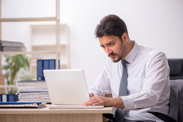 Young male employee and too much work in the office