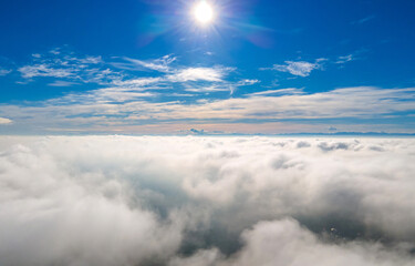 Aerial view from above of white puffy clouds in bright sunny day.