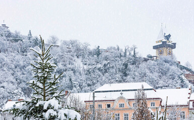 Heavy snow and the famous clock tower on Schlossberg hill, in Graz, Steiermark region, Austria. Selective focus