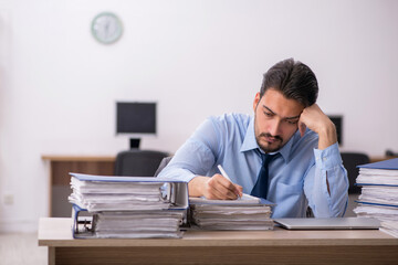 Obraz premium Young male employee and too much work in the office