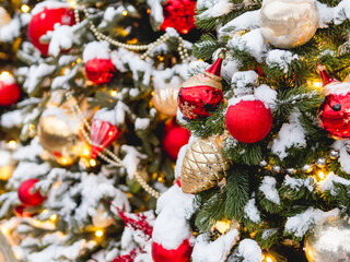 Christmas tree with colorful outdoor decorations. Fir tree decorated with light bulbs and Santa Claus symbol for New Year celebration.