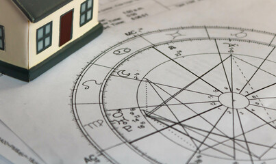 Printed natal chart with astrology moon with a toy house in the background