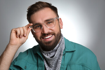 Obraz premium Fashionable young man in stylish outfit with bandana on grey background