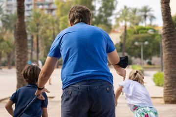 Family (father, son and daughter) playing running races in Valencia's Turia River
