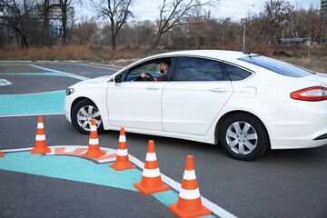 Young man in car on test track with traffic cones. Driving school