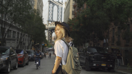 Fashion video of pretty woman near the Brooklyn Bridge in New York City at Sunrise. Young traveling woman in a hat enjoying American holidays.