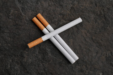 Three cigarettes on a textured gray stone. The concept of a healthy lifestyle.