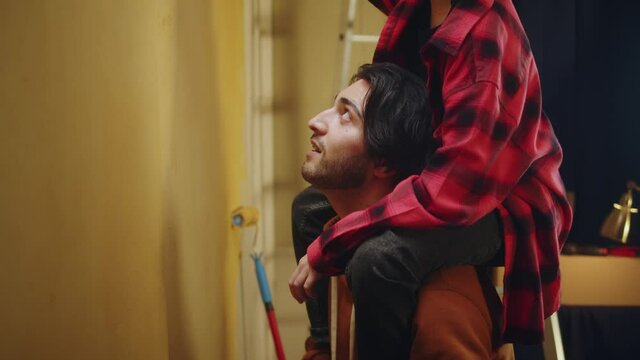Father and son painting walls in yellow, making overhaul together with child. Doing renovating with kid and having fun. Interior design, new apartment. Boy helping to his parent.