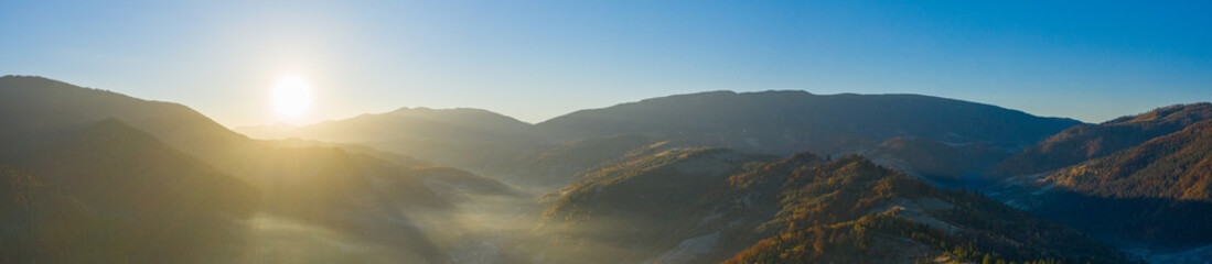 Mountain landscape. Autumn forest in the fog, dawn. Drone view