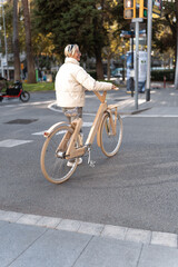 Positive woman with wooden eco bike crossing street