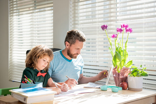 bearded dad writing school homework with his boy son in classroom, family day