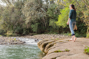Woman walking on rocks barefooted with her shoes in hands