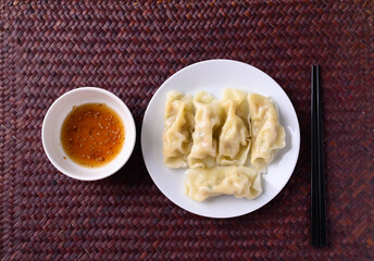Steamed wonton dumpling stuffed with minced pork on plate eating with sesame oil sauce, Asian food, Top view