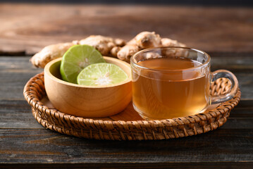 Ginger tea with lime in small basket on wooden background, Healthy herbal drink