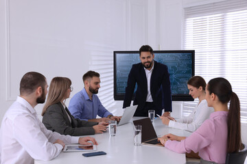 Business trainer near interactive board in meeting room during presentation