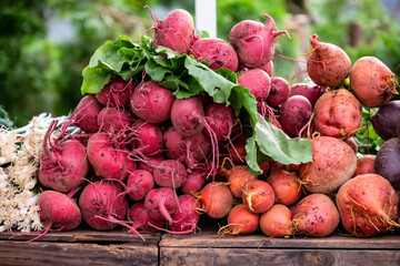 Fresh colorful beets, with greens, are statcked on a wooden table at a Farmers Market in Oregon.
