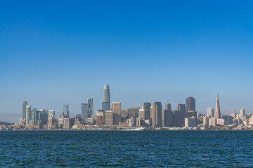 Naklejka premium A picturesque skyline of San Francisco Panorama at sunrise from Treasure Island, California, United States. Panoramic view of cityscape with mist and foggy air at morning day time.