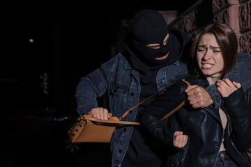 Woman fighting with thief while he trying to steal her bag outdoors at night. Self defense concept