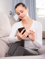 Young woman with a mobile phone on the sofa at home. High quality photo
