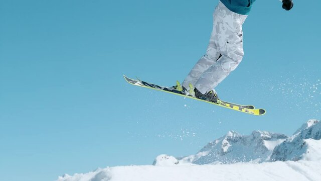 SLOW MOTION, CLOSE UP: Athletic male tourist rides off a snowpark kicker in Vogel and does a spectacular 360 grab. Expert freestyle skier rides up a kicker and does a spinning trick on a sunny day.