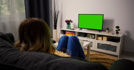 Woman Sitting on a Couch Home Watching Green Chroma Key Screen, Relaxing. Girl in a Cozy Room...
