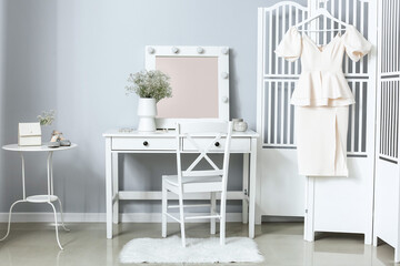 Interior of light dressing room with table, folding screen and gypsophila flowers in vase