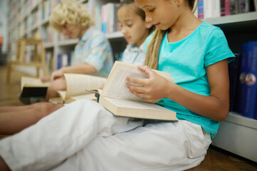 Girl leafing through book sitting with friends on floor