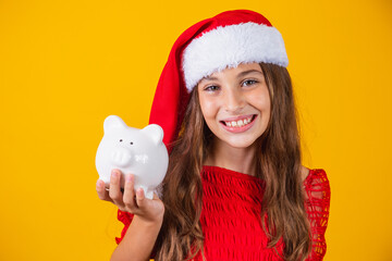 Smiling little girl with christmas hat holding piggy bank